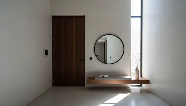 Vestíbulo vacío con panel de videoportero y luz de mediodía entrando por una ventana